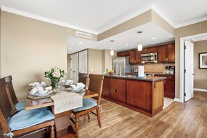 A modern kitchen with wooden cabinets, a central island, and a dining area with a table set for four.