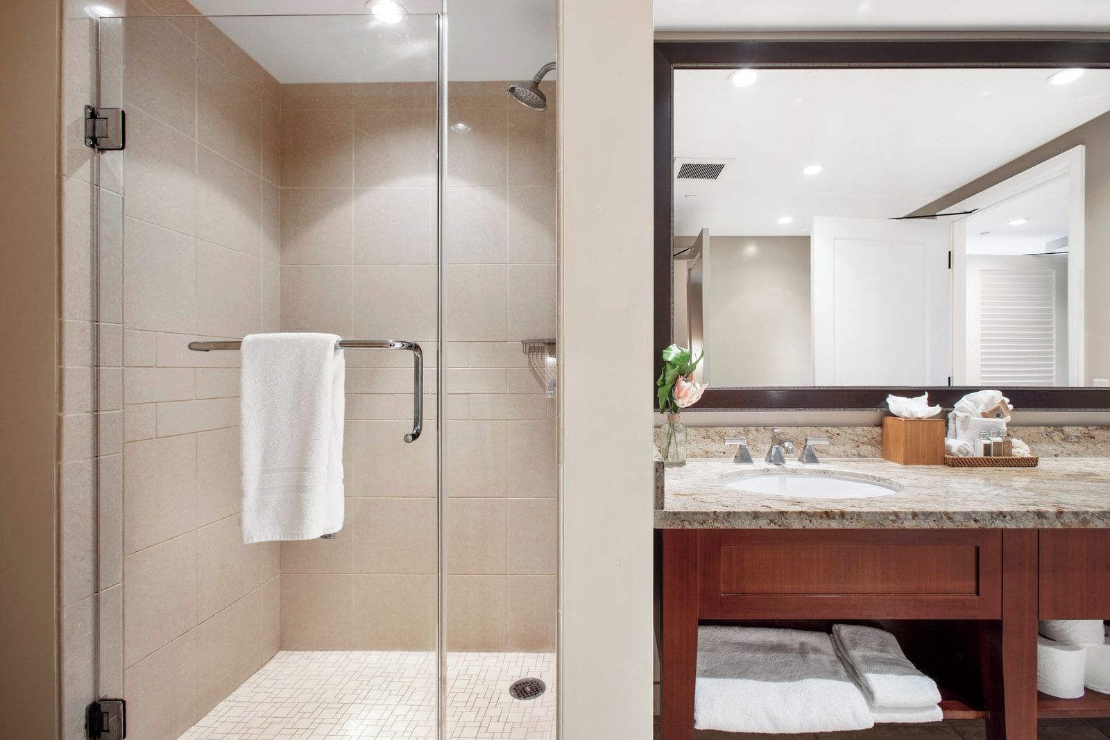 A modern bathroom with a glass-enclosed shower, a vanity with a marble countertop, and a large mirror.