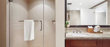 A modern bathroom with a glass-enclosed shower, a vanity with a marble countertop, and a large mirror.