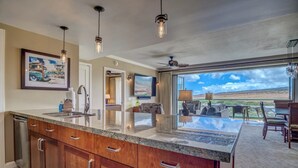 A spacious kitchen with granite countertops, wooden cabinets, and pendant lighting.