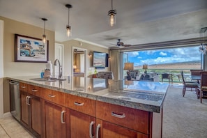A spacious kitchen with granite countertops, wooden cabinets, and pendant lighting.