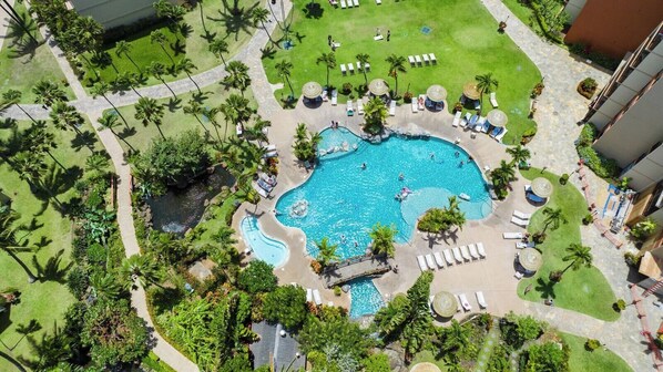 Ein großer Pool, umgeben von Palmen und Liegestühlen, mit einem steinernen Weg, der zum Pool führt.