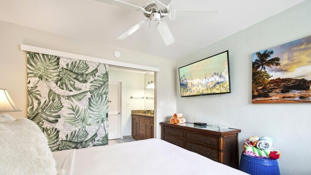 A bedroom with a bed, a ceiling fan, a TV, and artwork on the wall. - Napili Point | Oceanfront 3 BR, Sleeps 8 | Car Incl. w/ 6+ Nights | NAP ML-1541 by KBM (Lahaina)