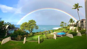 A lush garden with a pool, a view of the ocean, and a rainbow arching over the scene. - Napili Point | Oceanfront 3 BR, Sleeps 8 | Car Incl. w/ 6+ Nights | NAP ML-1541 by KBM (Lahaina)