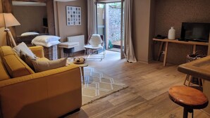 Una sala de estar moderna con sofá, sillón y comedor, además de un televisor.