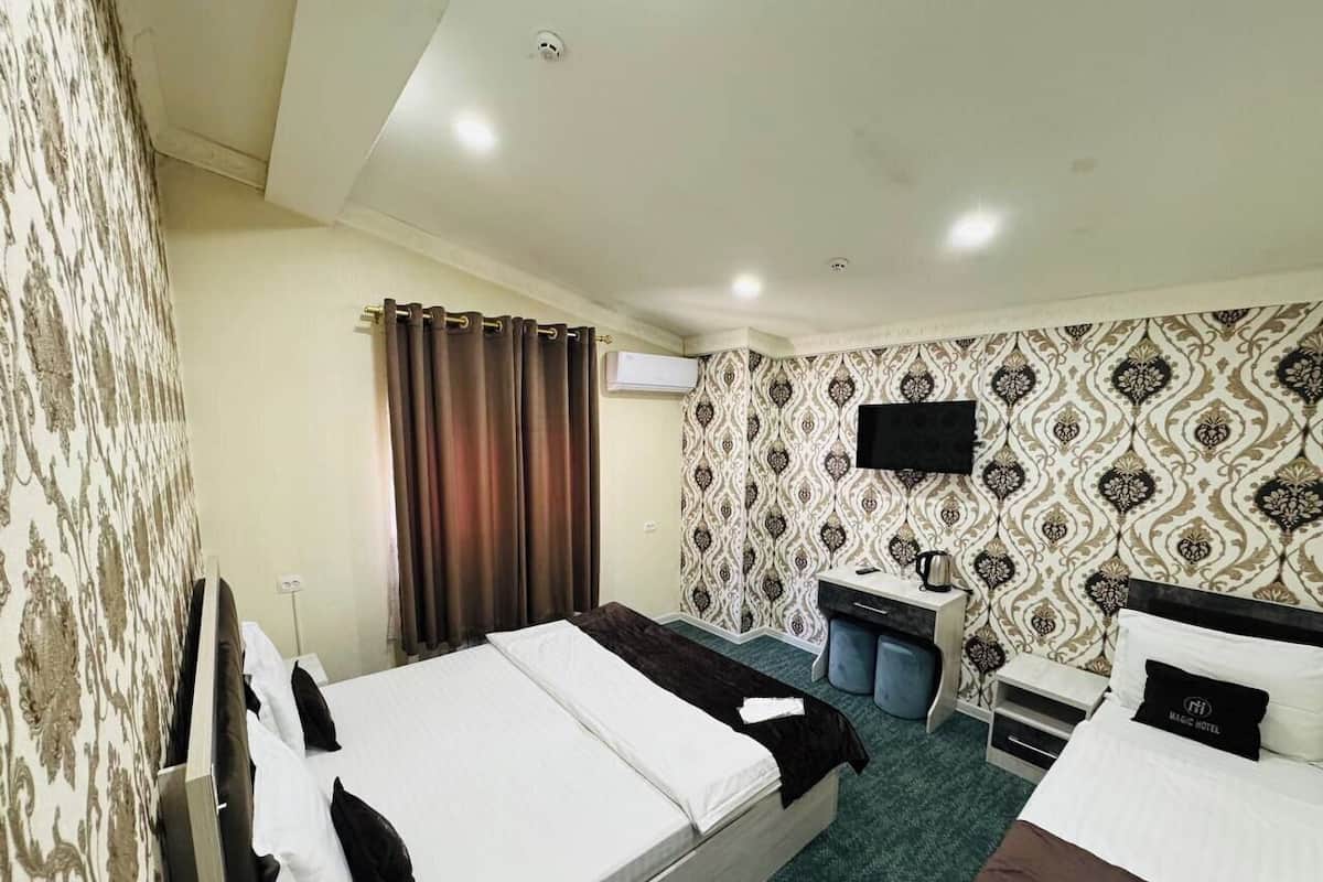 A hotel room with two beds, a desk, a chair, and a television.