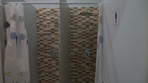 A shower area with a tiled wall, a showerhead, and a curtain with cloud patterns. - Rox Madrid Shared room (Madrid)