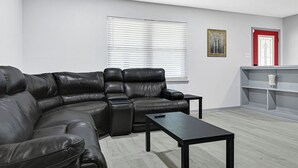 Una sala de estar moderna con un sofá modular, una mesa de centro, una estantería y una puerta con marco rojo.