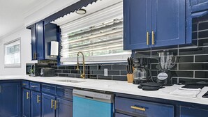 Una cocina moderna con armarios azules, un lavavajillas, una cafetera y una licuadora sobre la encimera.