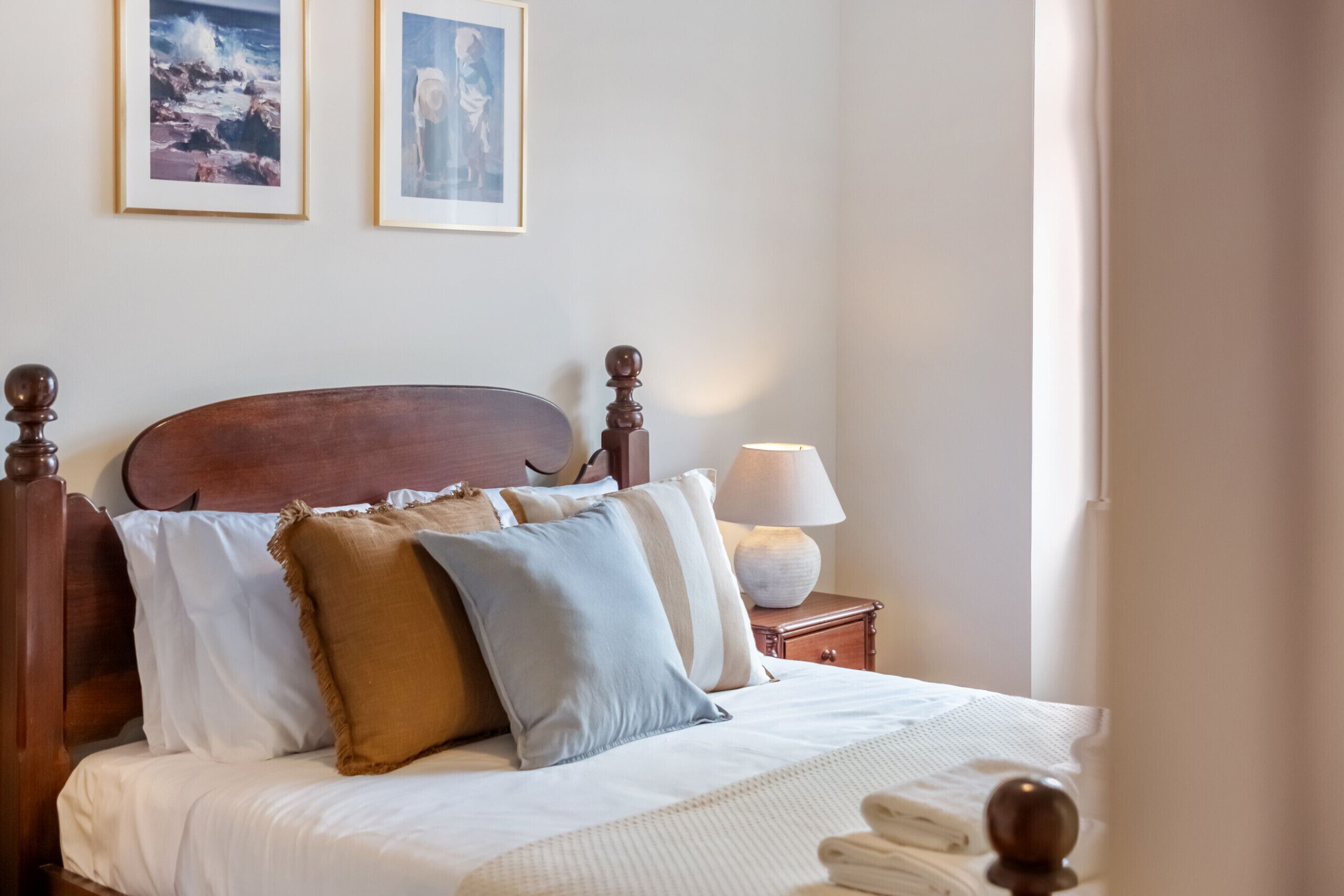 A neatly made bed with a wooden headboard, white linens, and several pillows.