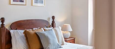 A neatly made bed with a wooden headboard, white linens, and several pillows.