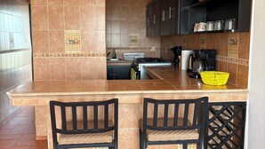A kitchen with two bar stools, a stove, and cabinets. - Unwind at this peaceful oasis. 3 minute drive to the beach (Manzanillo)