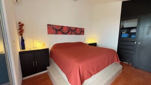 A bedroom with a bed, nightstands, a wall art piece, and a door with storage. - Unwind at this peaceful oasis. 3 minute drive to the beach (Manzanillo)
