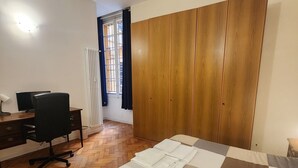 A bedroom with a wooden wardrobe, a desk with a chair, and a bed with a checkered bedspread. - TATA HOMES B&B (Bologna)