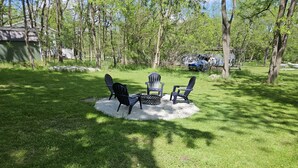 A circular outdoor seating area with Adirondack chairs and a fire pit. - New Renovation: 5BR Lake Delavan Retreat, Fire Pit, Huge Yard, Lake Access (Delavan)
