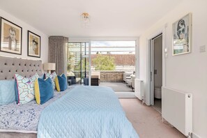 A bedroom with a large bed, a sofa, a balcony with a view, and a door leading to a bathroom. - The Hyde Park Townhouse (London)