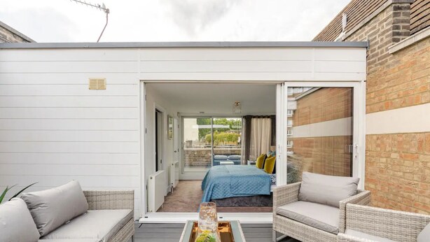 A modern outdoor living space with a balcony, wicker furniture, and a glass coffee table. - The Hyde Park Townhouse (London)