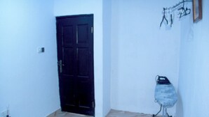 Una habitación con una puerta de madera oscura, una mesita con un bolso y un perchero de pared con objetos.
