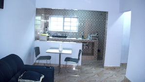 Un espacio habitable compacto con kitchenette, una zona de comedor con mesa y sillas, y un sofá.