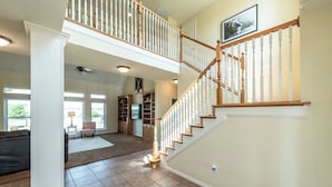 A spacious living area with a high ceiling, a wooden staircase, and a large rug on the floor. - Charming farmhouse in Countryside with Pool & great views for 16 guests  (Ponder)