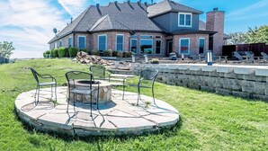 A large house with a brick exterior, a stone patio with outdoor furniture, and a well-maintained lawn. - Charming farmhouse in Countryside with Pool & great views for 16 guests  (Ponder)