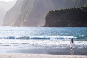 Une plage avec des vagues et une personne qui marche sur le sable.