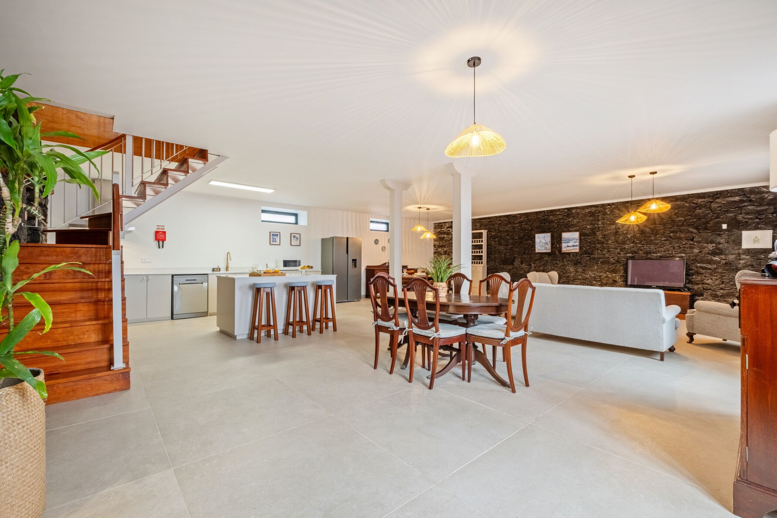 Amplia sala de estar con mesa y sillas de comedor, un sofá y una pared de acento de piedra.