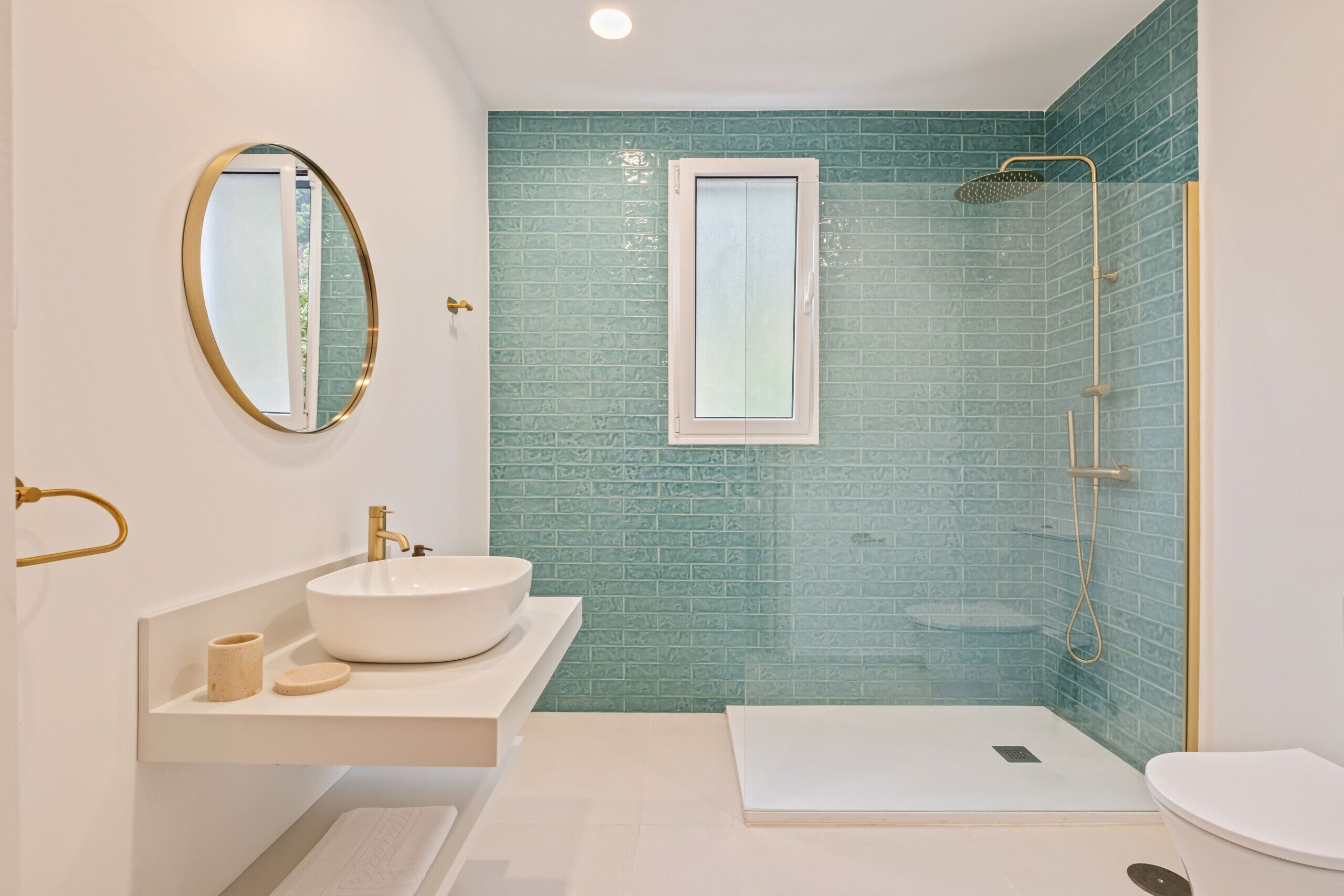 Une salle de bain moderne avec un lavabo blanc, un grand miroir, une fenêtre et un espace douche.