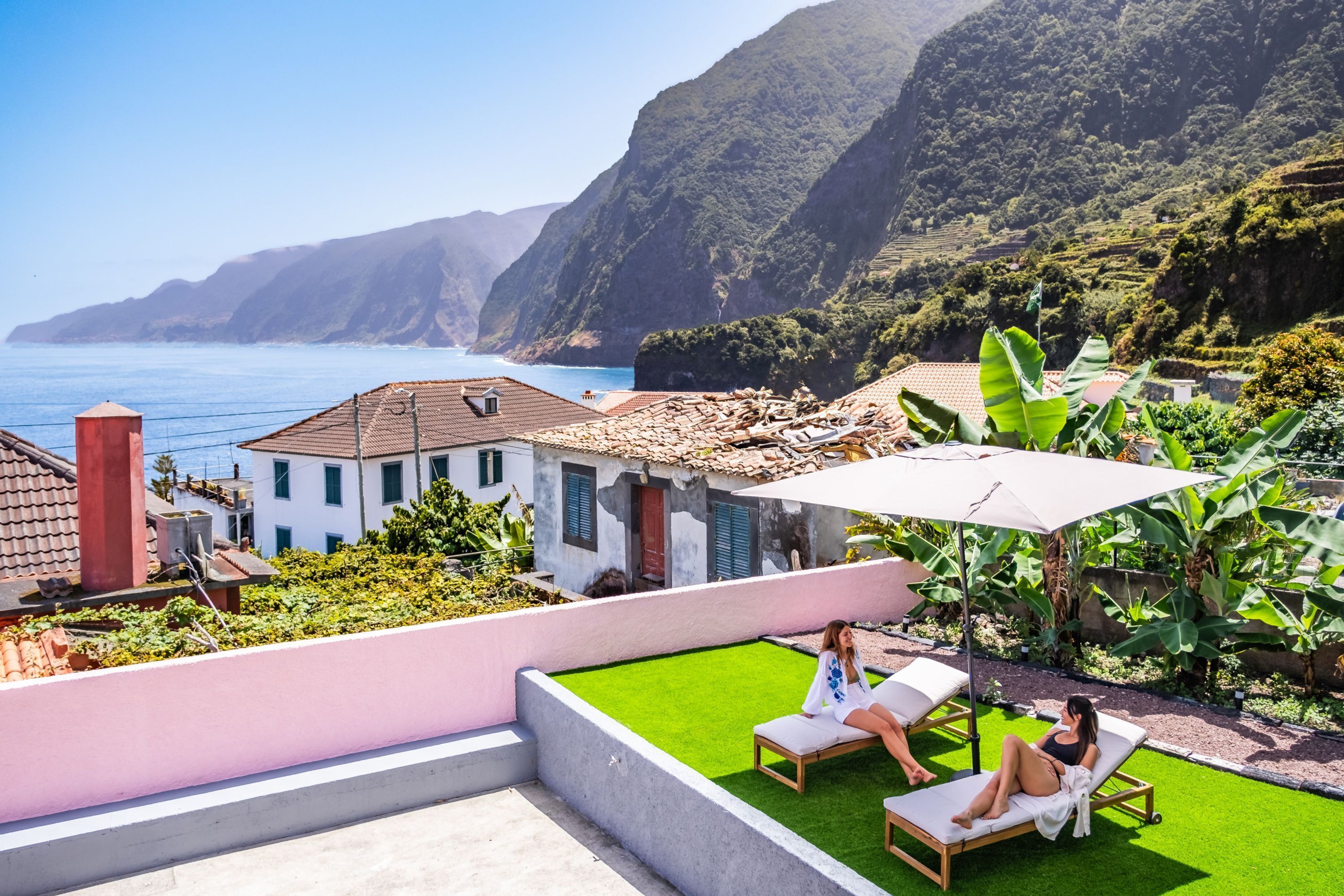 Imóvel residencial com pátio e vista para o litoral, com piscina e espreguiçadeiras.