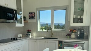 Una cocina moderna con armarios blancos, microondas, lavamanos y un comedor con mesa y sillas.