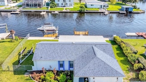 A modern house with a sloped roof, a small front yard, and a dock extending into a body of water. - SCALLOP TIME AT WATERFRONT ESCAPE DIRECT GULF ACCESS, GOLF CART & KAYAKS. (Hernando Beach)