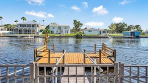 A wooden dock leading to a calm water body with houses in the background. - SCALLOP TIME AT WATERFRONT ESCAPE DIRECT GULF ACCESS, GOLF CART & KAYAKS. (Hernando Beach)