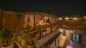 A multi-level outdoor terrace with potted plants, a covered seating area, and a staircase. - Riad tala (Marrakech)