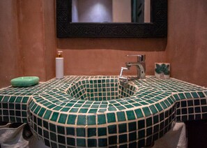 A bathroom with a green-tiled sink, a mirror above it, and a soap dispenser on the left. - Riad tala (Marrakech)