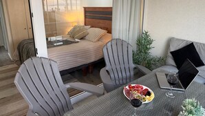 A hotel room with a bed, two chairs, a table with a laptop and a glass of wine, and a plate of fruit. - Modern Apartment with Ocean View and Heated Swimming Pool (La Serena)