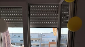 Una habitación con puerta de vidrio corrediza que da a un balcón con mesa y sillas.