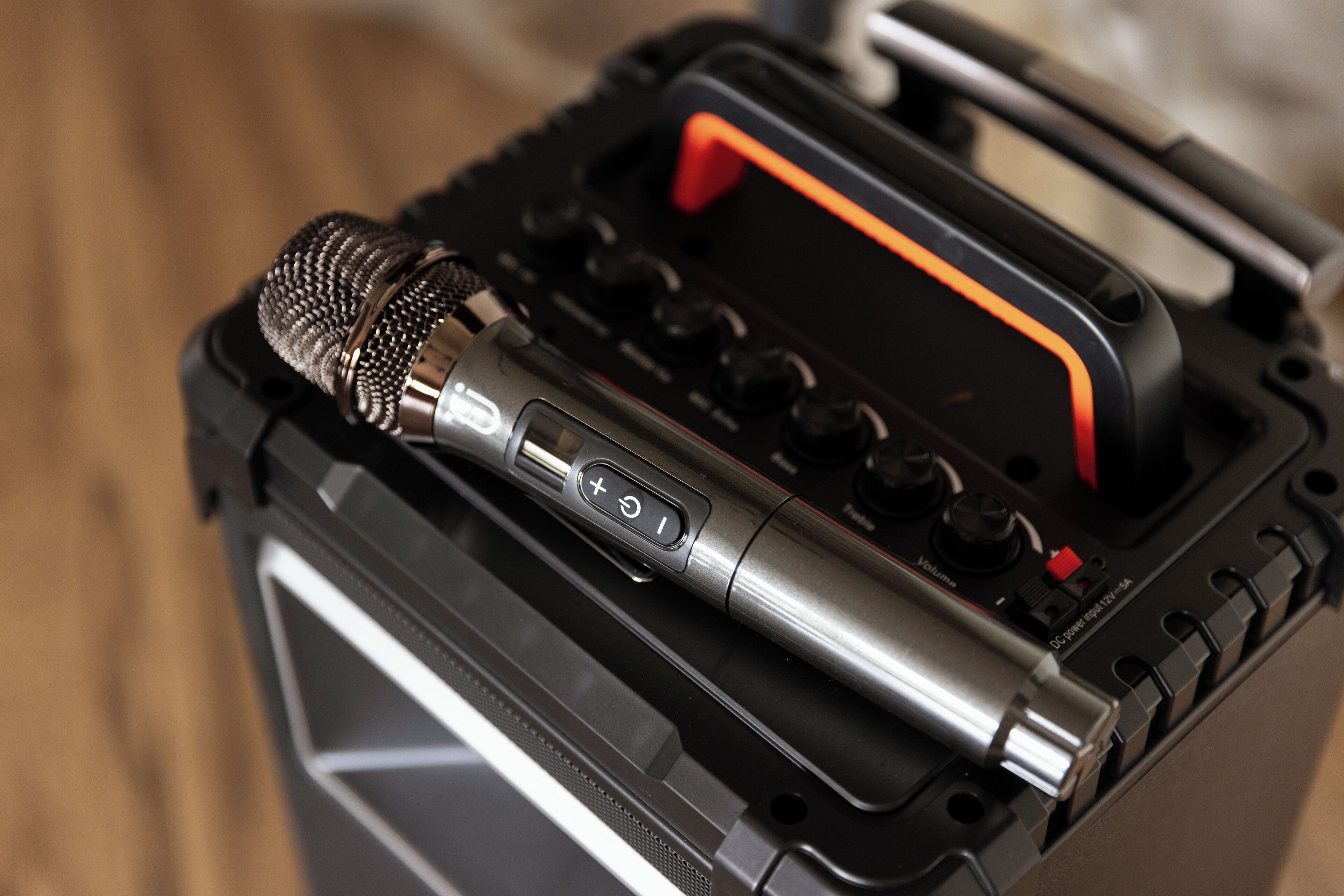 A portable audio mixer with a microphone and control knobs, placed inside a black case with a handle.