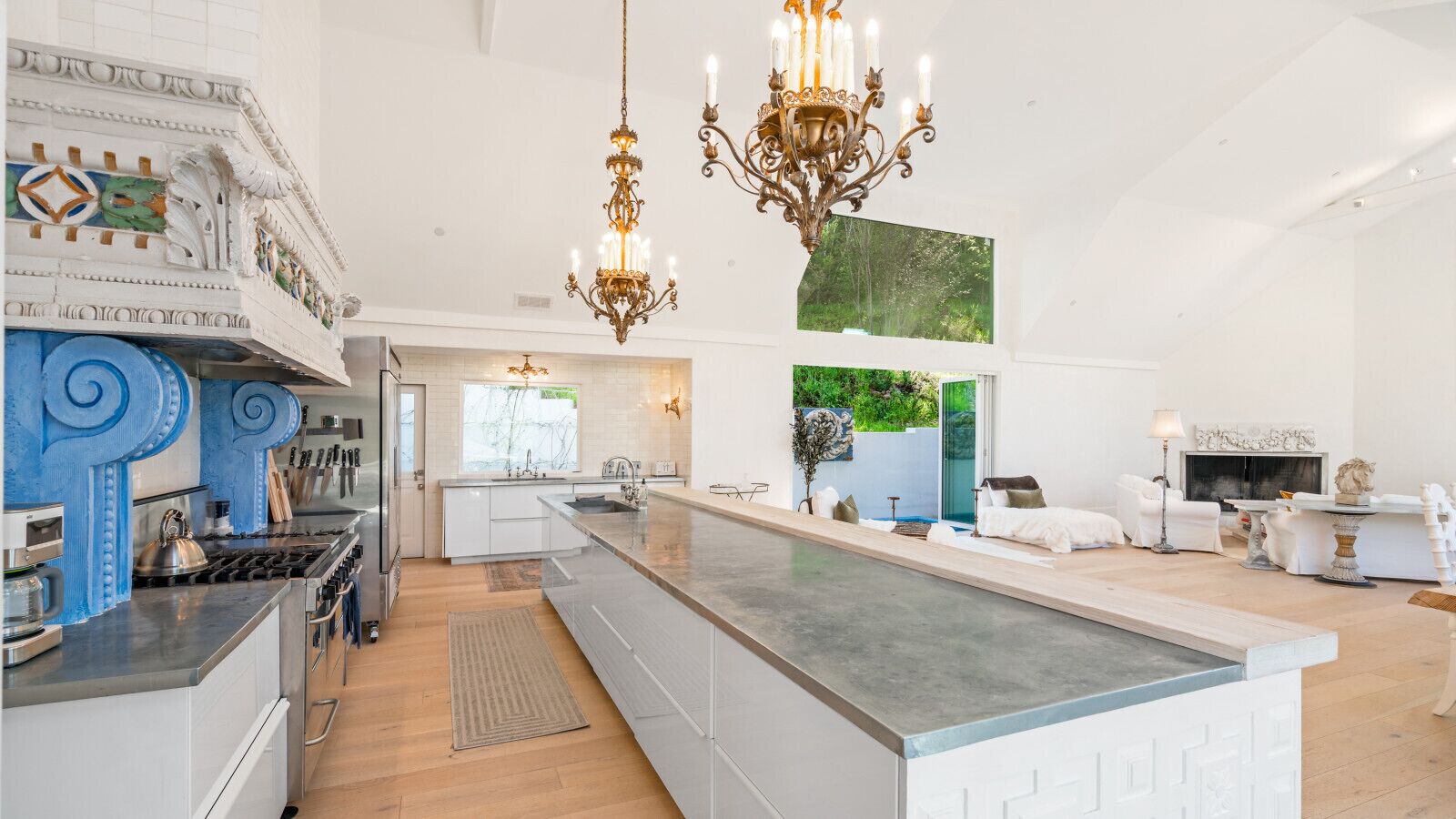 Een ruime keuken met een centraal eiland, een eethoek met witte meubels, en een woonkamer met een open haard.