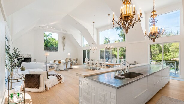A spacious kitchen with a large island, modern chandeliers, and large windows offering views of the outdoors. - Kenwood Lodge - 5 Bedroom/En-suite, Heated Pool (Kenwood)