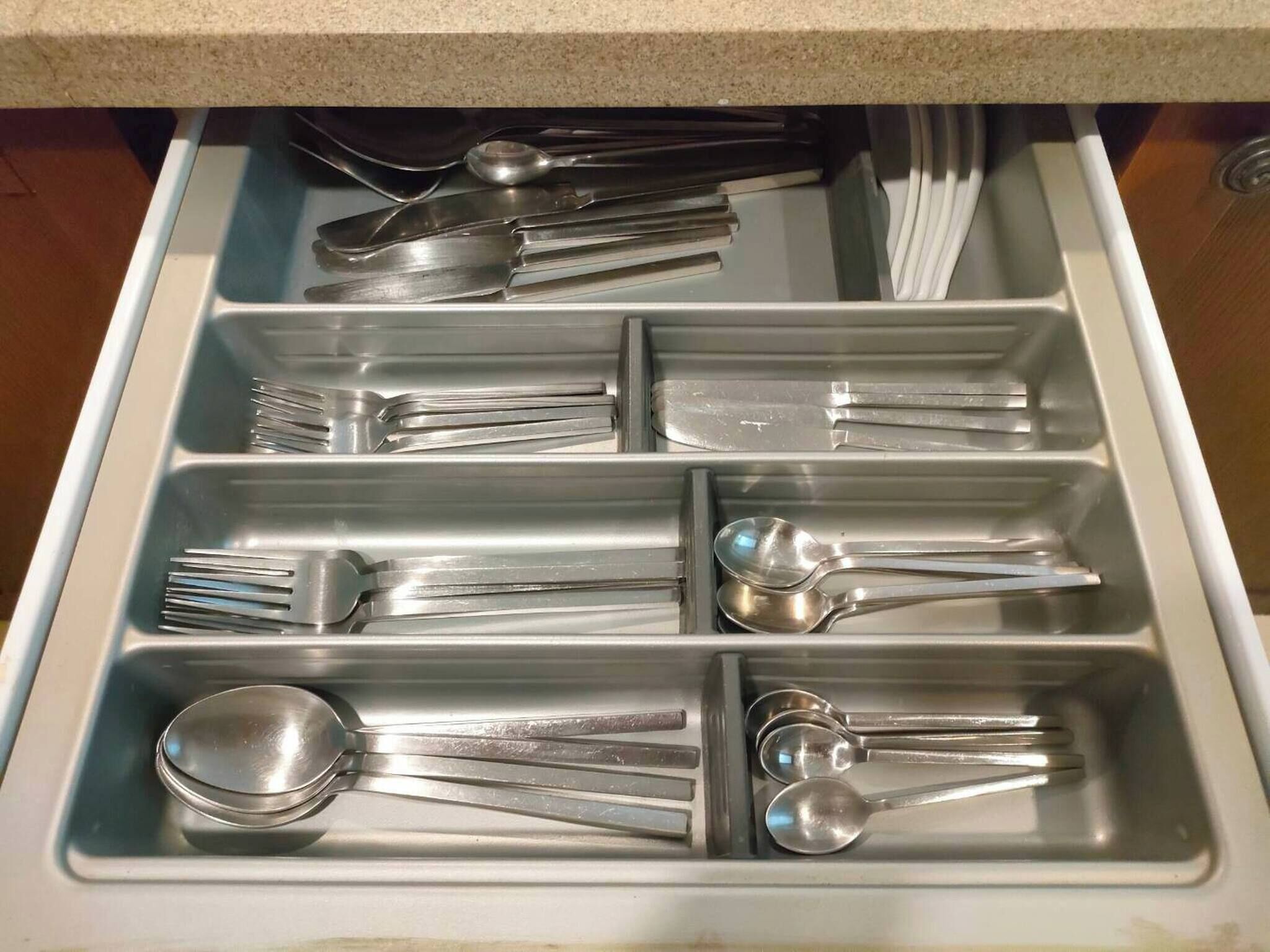 A drawer with multiple compartments containing various kitchen utensils.