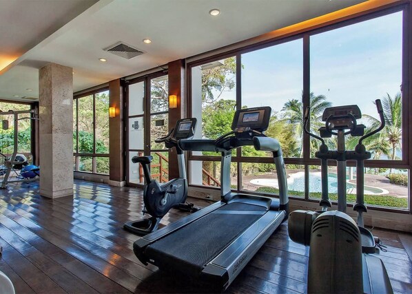 A gym with cardio machines and a pool view. - C Shasa Vela Condominium, Mared, Koh Samui (Koh Samui)
