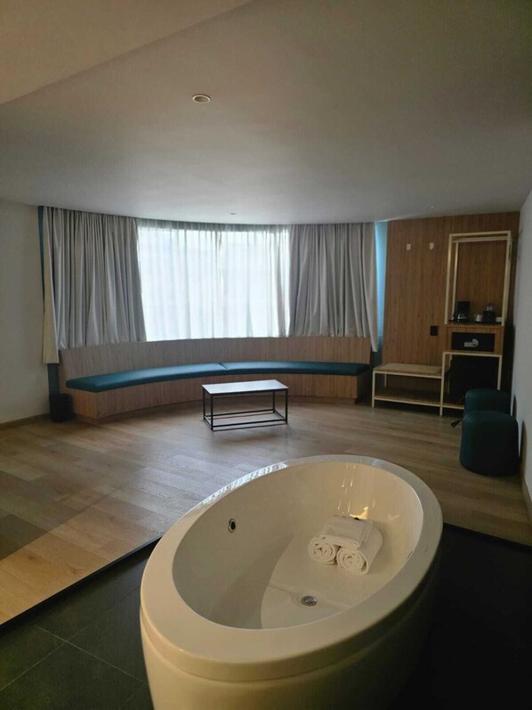 Ein modernes Zimmer mit einer großen Badewanne, einer Sitzbank am Fenster und einem kleinen Tisch.