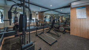 Un gimnasio con diverso equipo de ejercicio, incluyendo cintas de correr, máquinas de pesas y pesas sueltas.