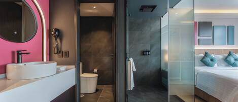 A modern bathroom with a glass shower enclosure, a white sink, and a mirror with a pink accent wall.