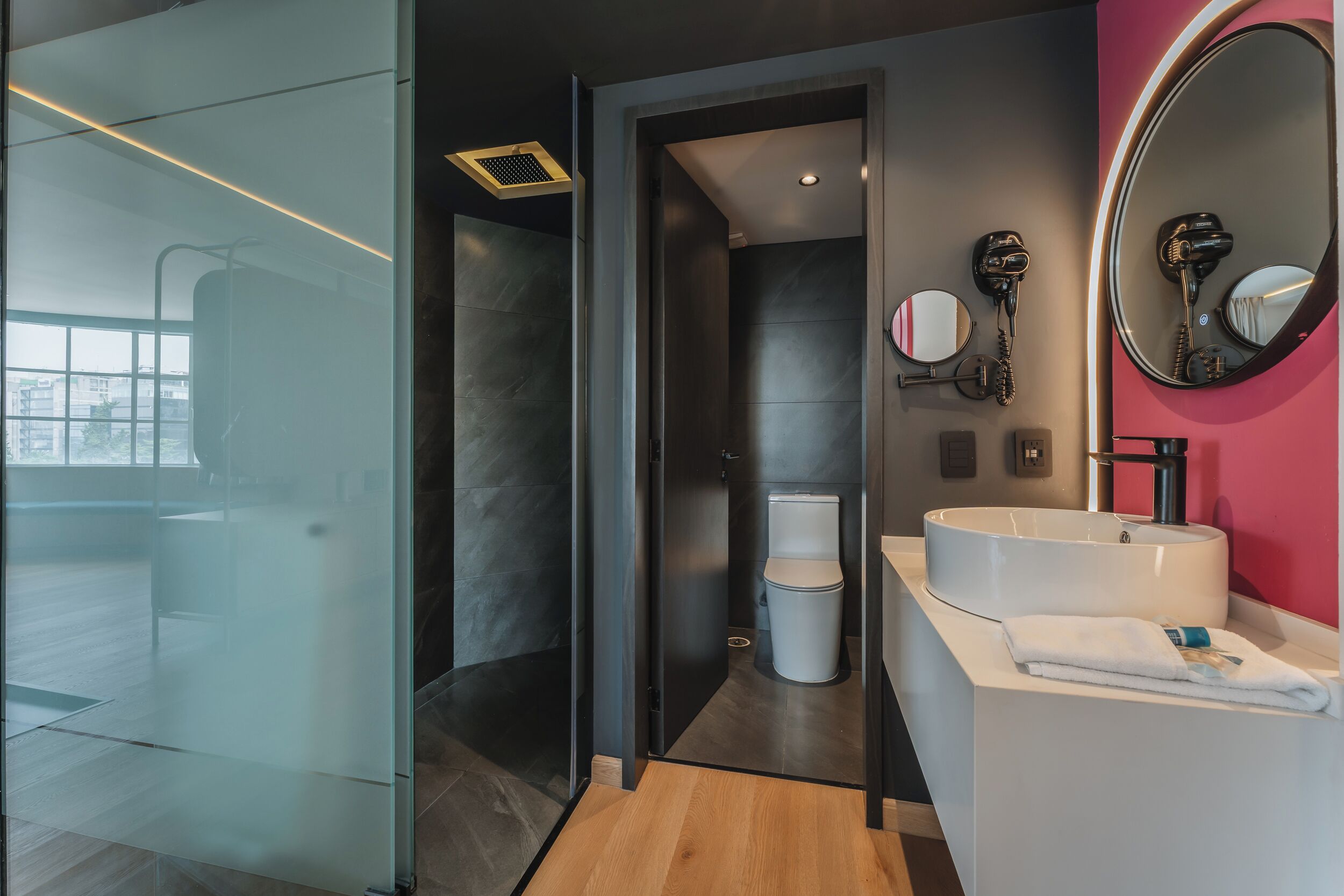 Un baño moderno con cabina de ducha de vidrio, un lavabo blanco y un espejo de tocador.