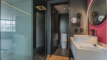 Un baño moderno con cabina de ducha de vidrio, un lavabo blanco y un espejo de tocador.