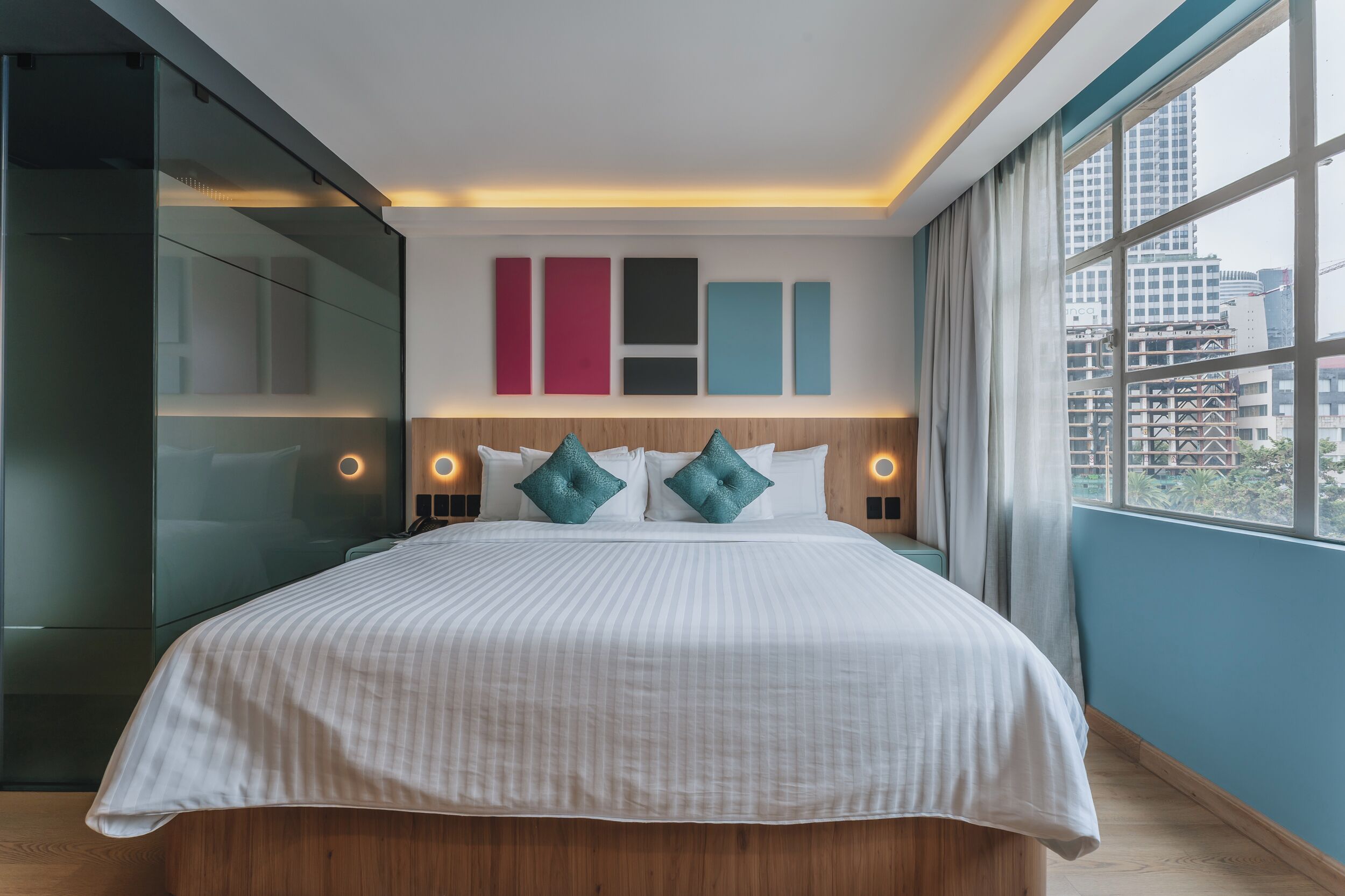 Una habitación de hotel moderna con una cama grande, vistas a la ciudad y un diseño minimalista.