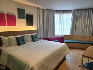 Ein Hotelzimmer mit einem großen Bett, einem Schreibtisch, einem Sessel und einer Bank.
