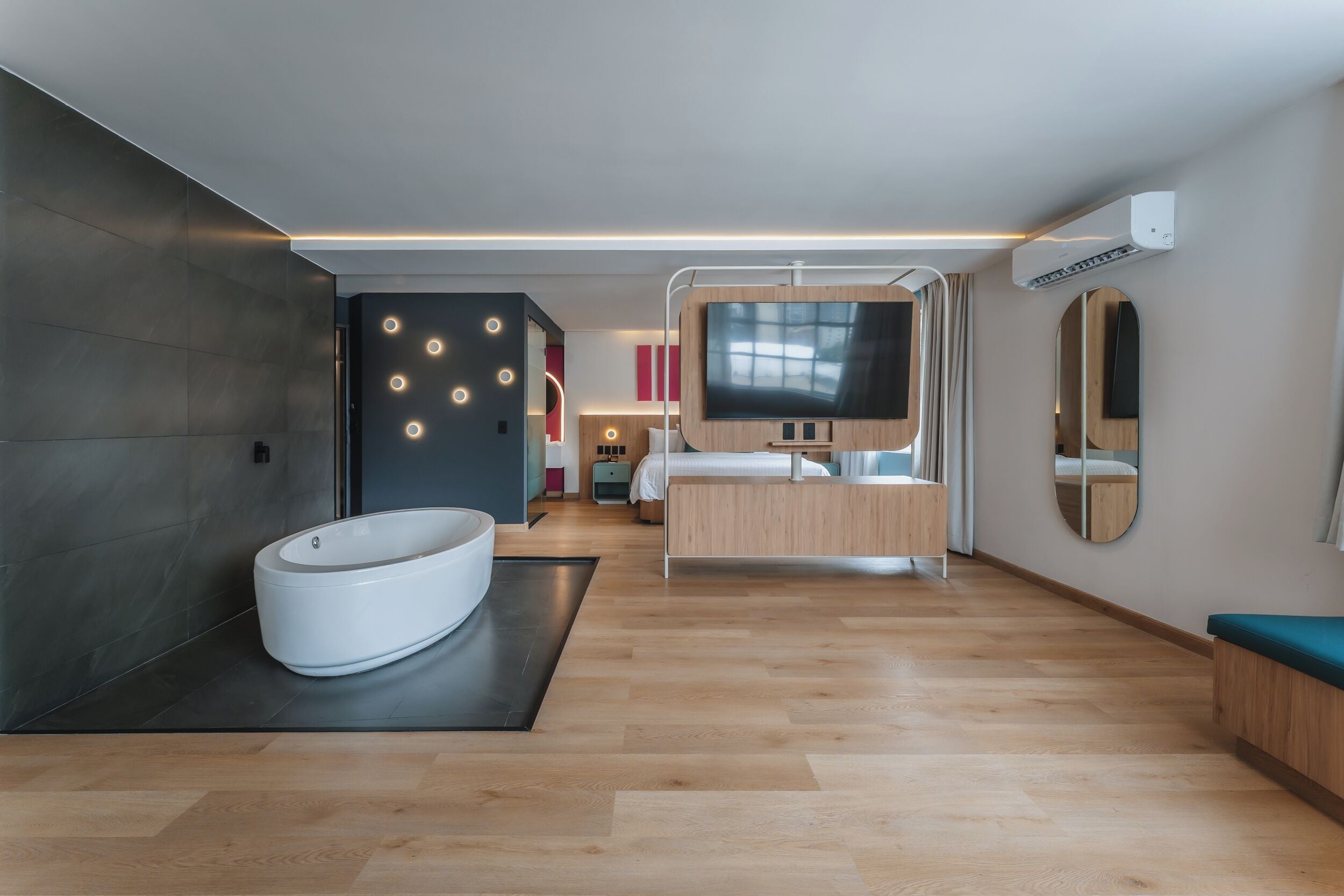 Une chambre d’hôtel moderne équipée d’une grande baignoire, d’un lit, d’une télévision et d’un miroir.