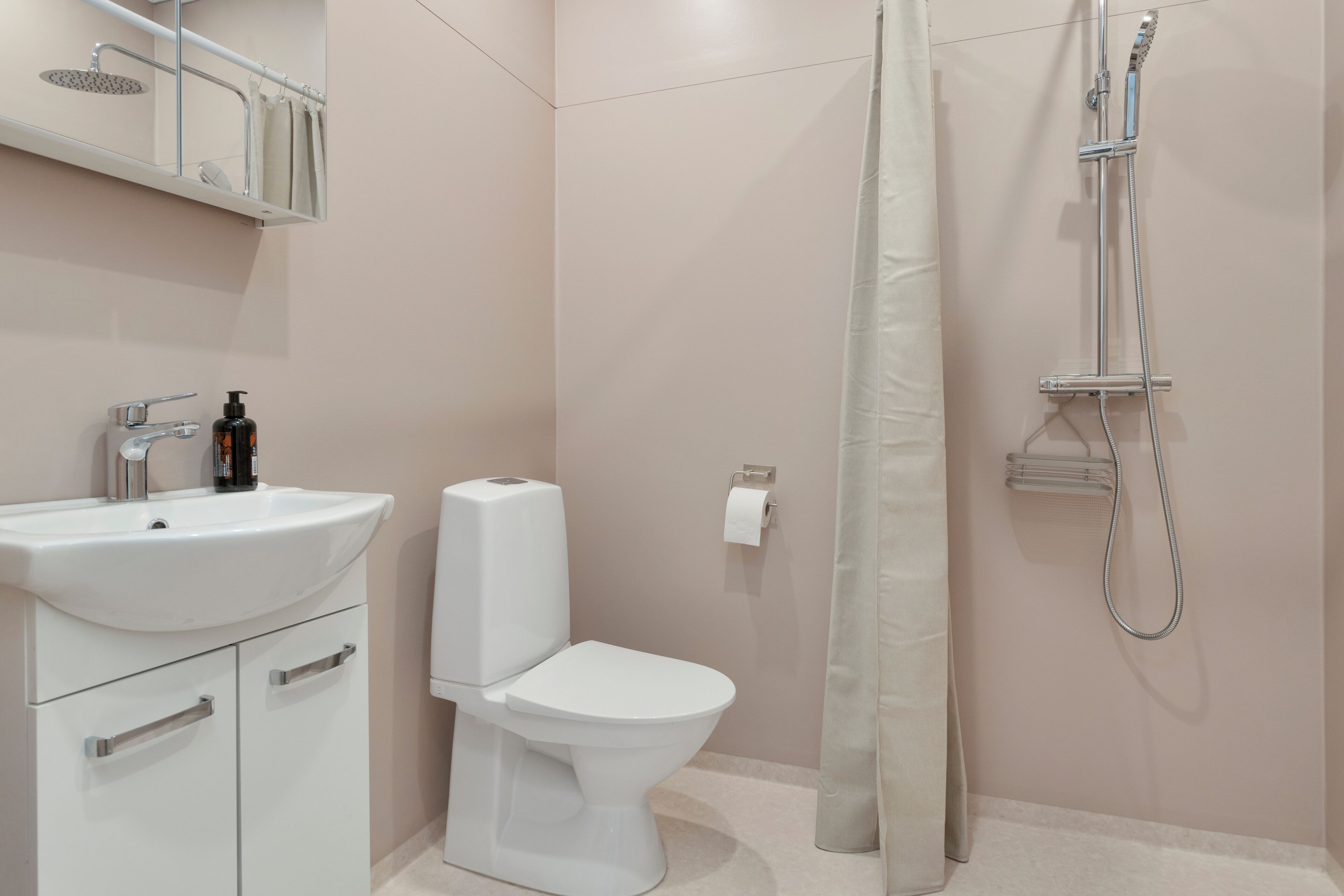 Een moderne badkamer met een wit wastafel, toilet en douche.